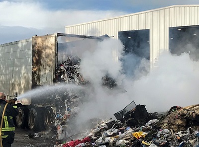 Fireman extinguishing a fire that started in a trash hauler