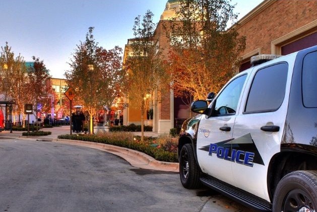 police car against a backdrop of retail stores at the Village in Meridian