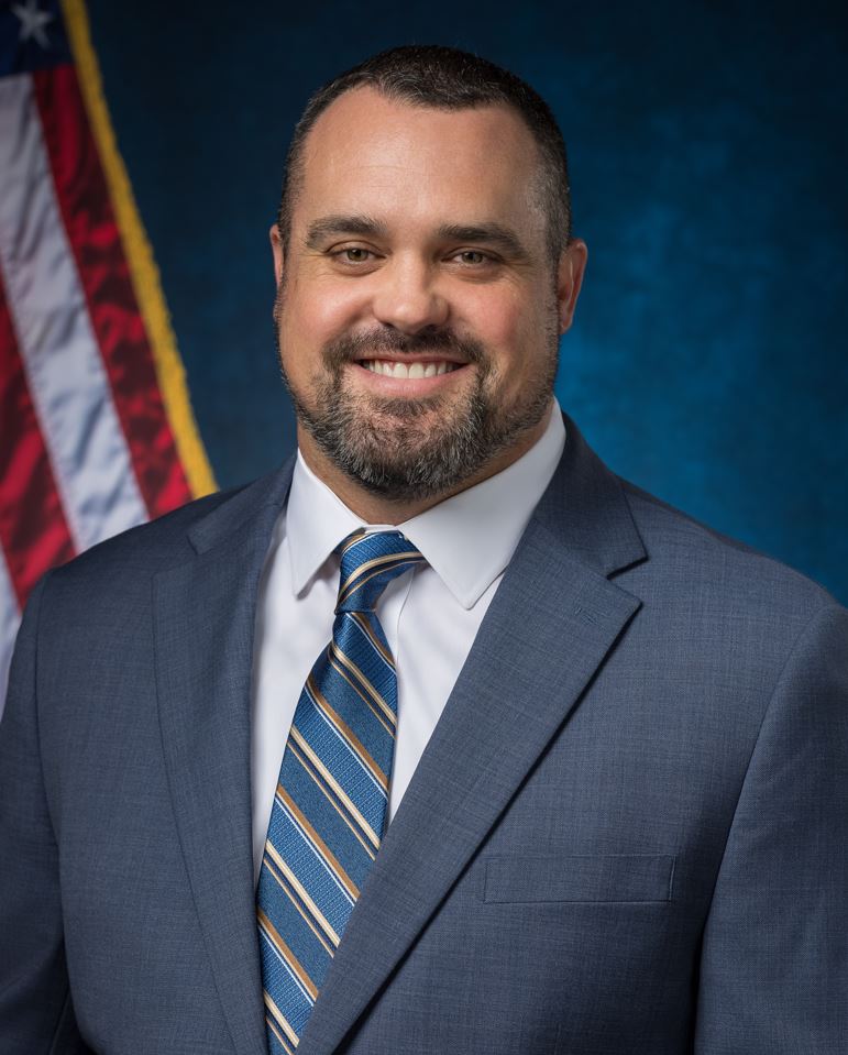 Doug Taylor with blue background and U.S. flag