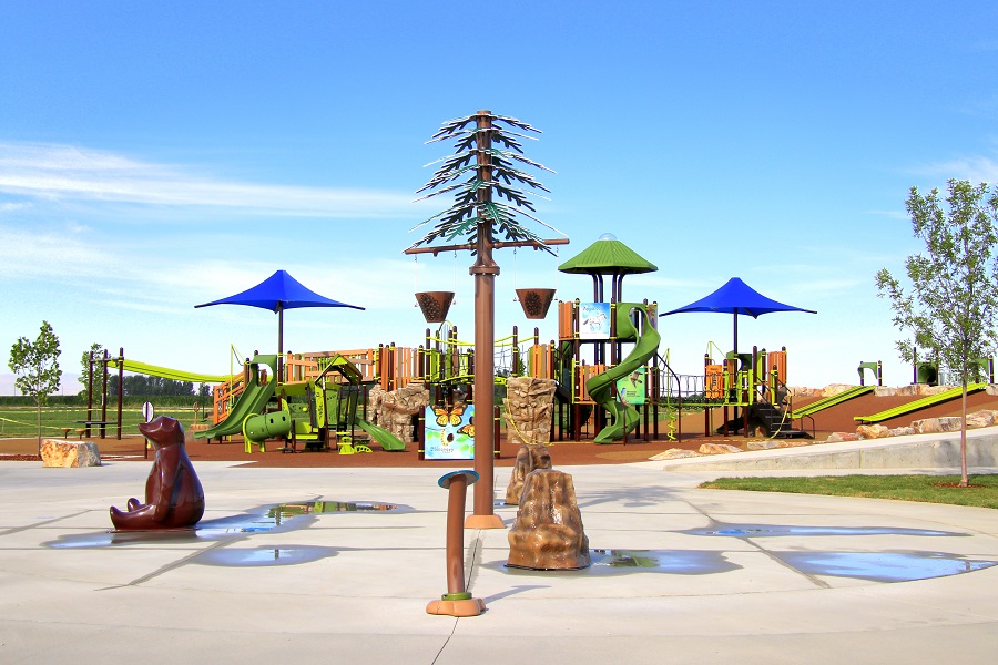 Splash pad with water features in the shapes of a bear, a tree, and rocks at Discovery Park