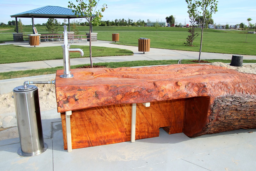 Water feature including a large log and pump in sand and water play area at Discovery Park