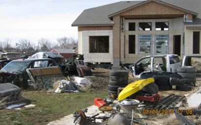 Photo of house with large amounts of junk such as tires and vehicles in yard