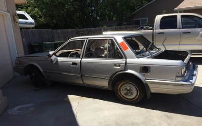 Photo of broken down car with pieces missing parked on private property