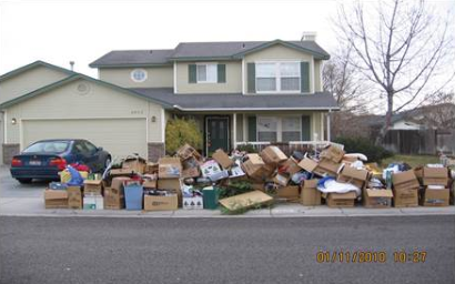 Photo of dozens of boxes piled on sidewalk in front of a house