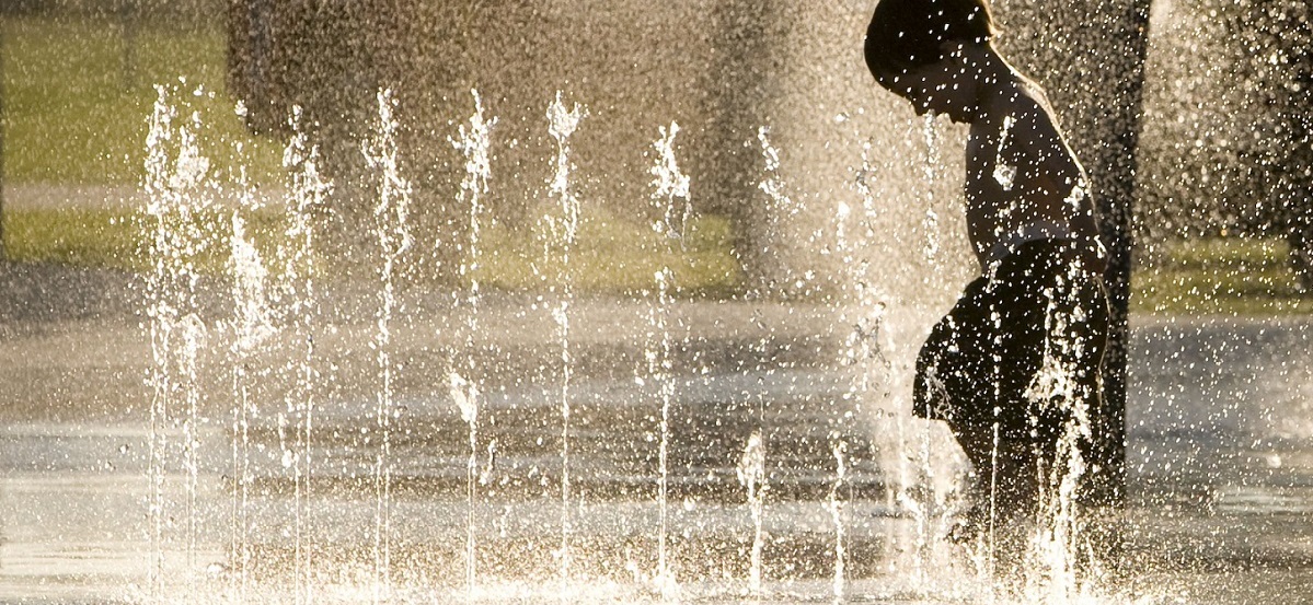 a child playing among water droplets suspended in the air by a decorative fountain